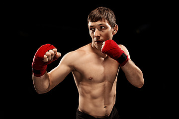 Image showing Male boxer boxing in punching bag with dramatic edgy lighting in a dark studio