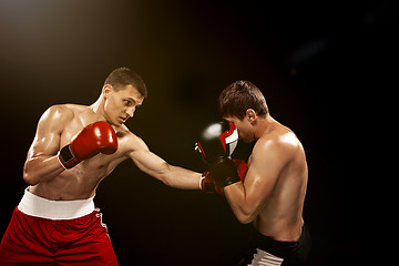 Image showing Two professional boxer boxing on black background,