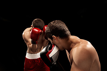 Image showing Two professional boxer boxing on black background,