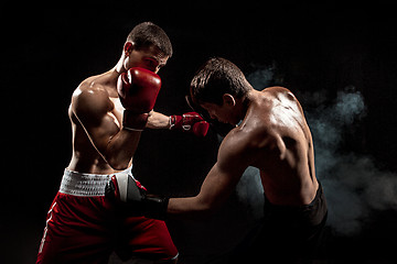 Image showing Two professional boxer boxing on black smoky background,