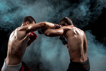 Image showing Two professional boxer boxing on black smoky background,