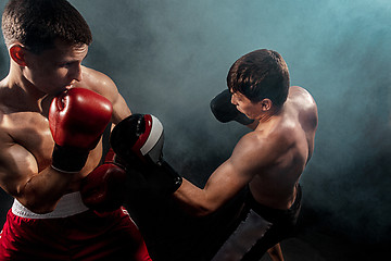 Image showing Two professional boxer boxing on black smoky background,