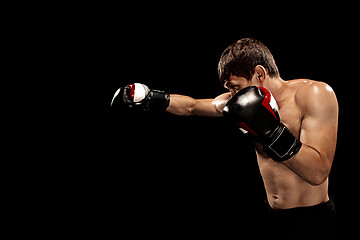 Image showing Male boxer boxing in punching bag with dramatic edgy lighting in a dark studio