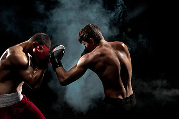 Image showing Two professional boxer boxing on black smoky background,