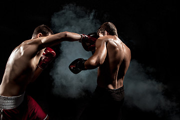 Image showing Two professional boxer boxing on black smoky background,