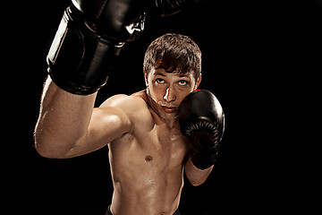 Image showing Male boxer boxing in punching bag with dramatic edgy lighting in a dark studio