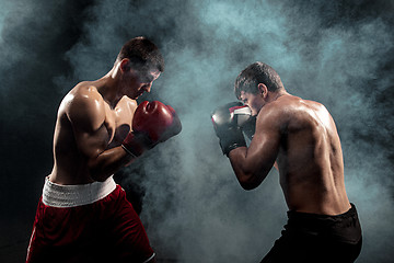 Image showing Two professional boxer boxing on black smoky background,