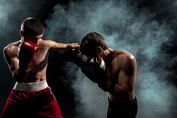 Image showing Two professional boxer boxing on black smoky background,