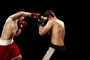 Image showing Two professional boxer boxing on black background,