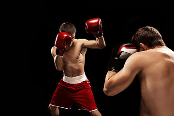 Image showing Two professional boxer boxing on black background,