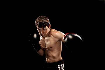 Image showing Male boxer boxing in punching bag with dramatic edgy lighting in a dark studio