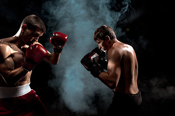 Image showing Two professional boxer boxing on black smoky background,