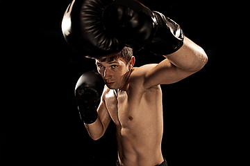 Image showing Male boxer boxing in punching bag with dramatic edgy lighting in a dark studio