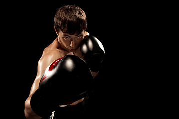 Image showing Male boxer boxing in punching bag with dramatic edgy lighting in a dark studio