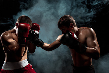 Image showing Two professional boxer boxing on black smoky background,