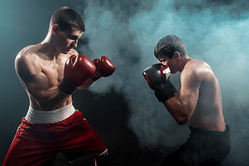 Image showing Two professional boxer boxing on black smoky background,