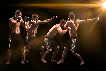 Image showing Male boxer boxing in punching bag with dramatic edgy lighting in a dark studio