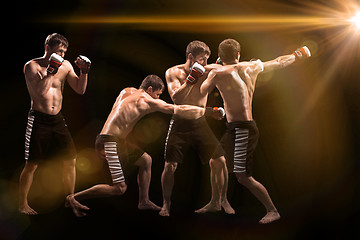 Image showing Male boxer boxing in punching bag with dramatic edgy lighting in a dark studio