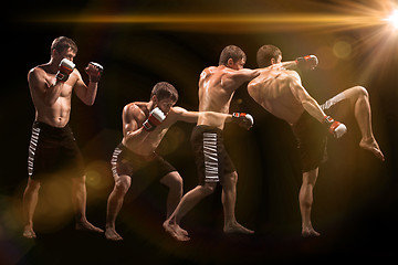 Image showing Male boxer boxing in punching bag with dramatic edgy lighting in a dark studio