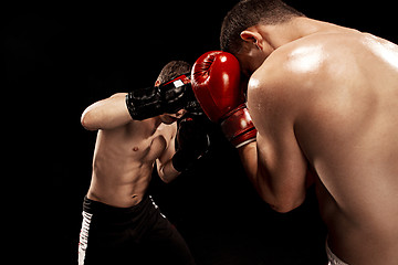 Image showing Two professional boxer boxing on black background,