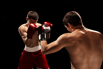 Image showing Two professional boxer boxing on black background,