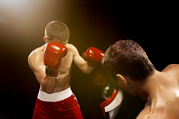 Image showing Two professional boxer boxing on black background,