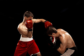 Image showing Two professional boxer boxing on black smoky background,