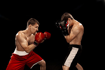 Image showing Two professional boxer boxing on black background,