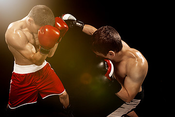 Image showing Two professional boxer boxing on black background,