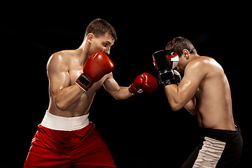 Image showing Two professional boxer boxing on black background,