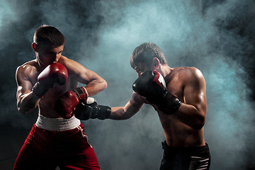 Image showing Two professional boxer boxing on black smoky background,