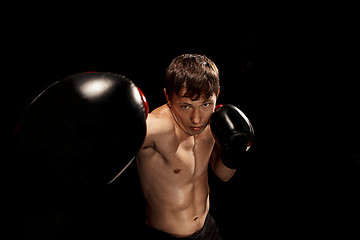 Image showing Male boxer boxing in punching bag with dramatic edgy lighting in a dark studio