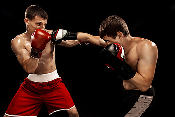 Image showing Two professional boxer boxing on black background,