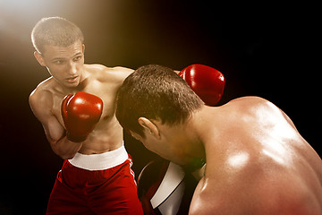 Image showing Two professional boxer boxing on black background,