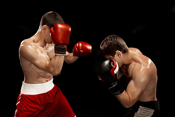 Image showing Two professional boxer boxing on black background,