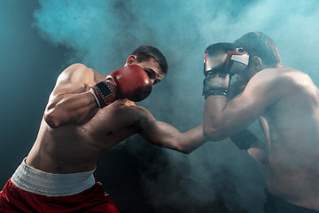 Image showing Two professional boxer boxing on black smoky background,