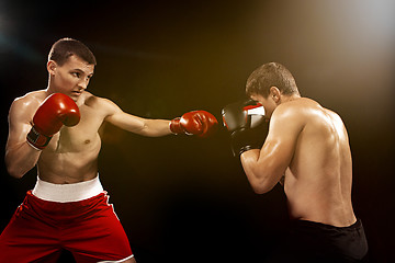 Image showing Two professional boxer boxing on black background,