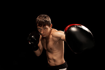 Image showing Male boxer boxing in punching bag with dramatic edgy lighting in a dark studio