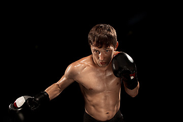 Image showing Male boxer boxing in punching bag with dramatic edgy lighting in a dark studio