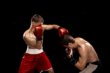 Image showing Two professional boxer boxing on black background,