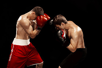 Image showing Two professional boxer boxing on black background,