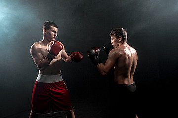 Image showing Two professional boxer boxing on black smoky background,