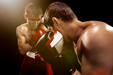 Image showing Two professional boxer boxing on black background,