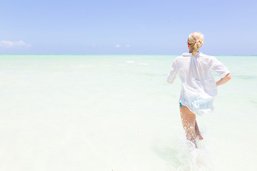 Image showing Young active woman having fun running and splashing in shellow sea water.