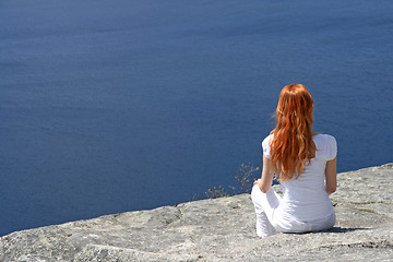 Image showing Red-haired girl looking over blue water