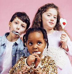 Image showing lifestyle people concept: diverse nation children playing together, caucasian boy with african little girl holding candy happy smiling 