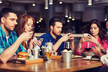 Image showing friends with smartphones dining at restaurant
