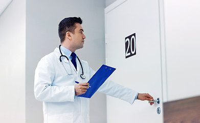 Image showing doctor with clipboard opening hospital ward door