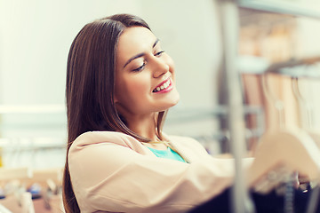 Image showing happy young woman choosing clothes in mall