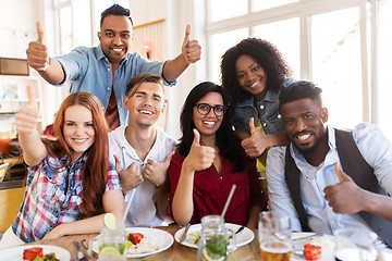 Image showing happy friends showing thumbs up at restaurant